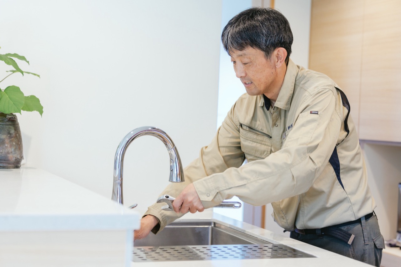 リフォームしたキッチンの水栓を確認するスタッフ